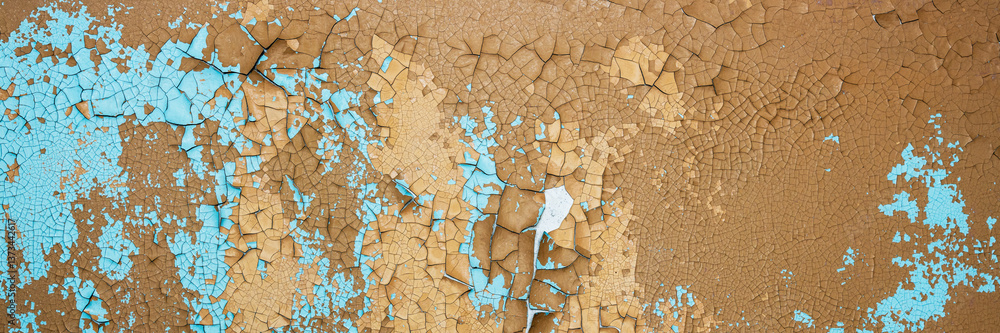 Peeling paint on the wall. Panorama of a concrete wall with old cracked flaking paint. Weathered rough painted surface with patterns of cracks and peeling. Wide panoramic grunge texture for background