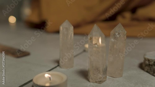 A close-up of three cone-shaped transparent crystals standing on the floor in a room among candles. Beautiful gems. Preparation for meditation.