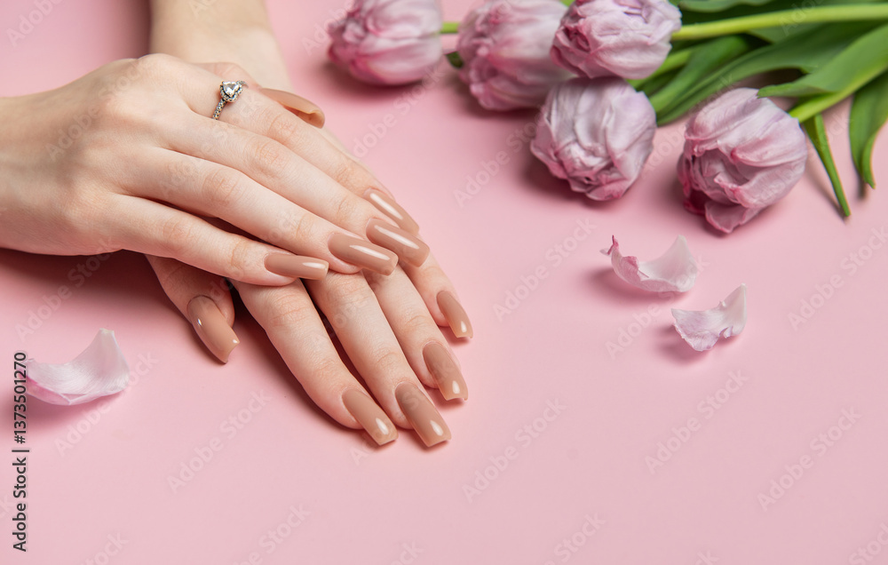 Fototapeta premium Woman showing stylish nude manicure near pink tulips on pink background