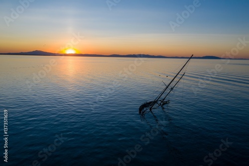 Bild auf Leinwand A sunken sailboat rests in calm waters at sunset in San Pablo Bay, Rodeo, California, USA
