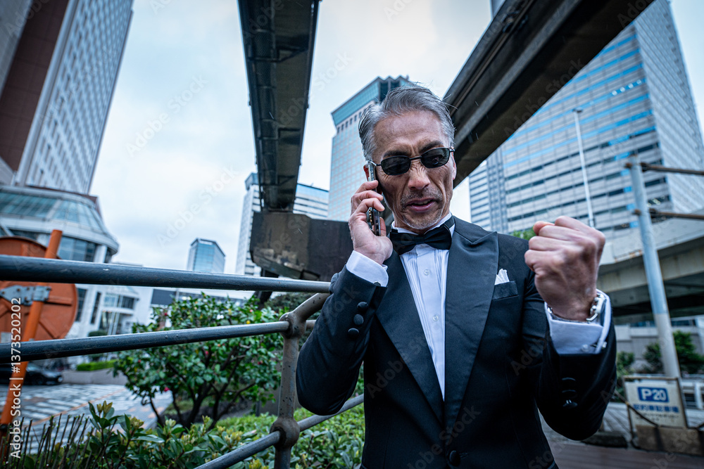 高架下のオフィス街で電話するビジネスマン