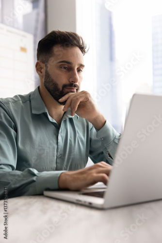 Canvastavla Focused pensive handsome Latin businessman working at laptop in office, touching face and chin in deep thoughts, thinking on online sales growth, Internet marketing strategy