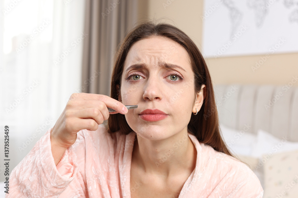 Beautiful woman plucking her mustache with tweezers at home Beautiful woman plucking her mustache with tweezers at home