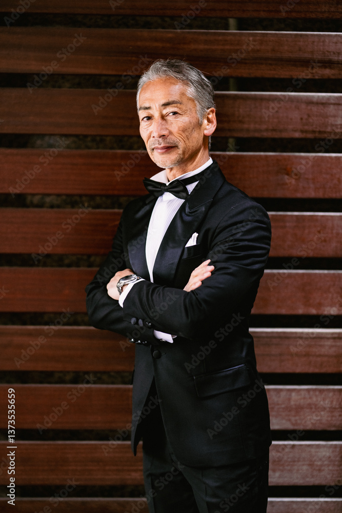 木製の壁を背にタキシードを着たシニア男性のポートレート