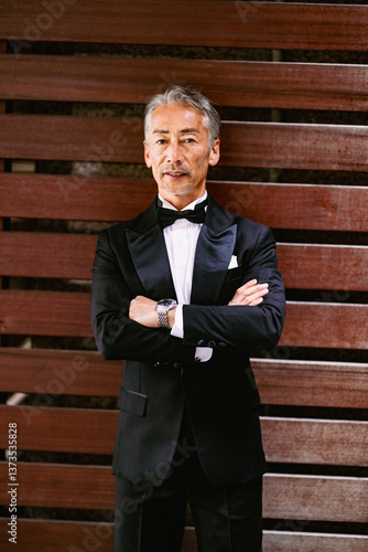 木製の壁を背にタキシードを着たシニア男性のポートレート