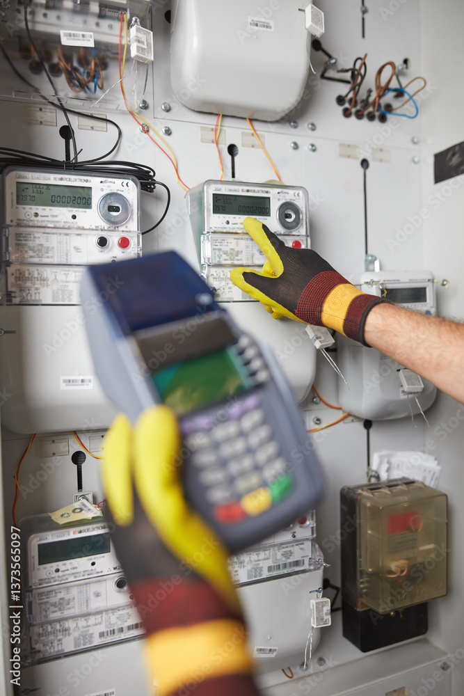 Technician reading consumption and charging on a wireless electricity power meter station in a building.