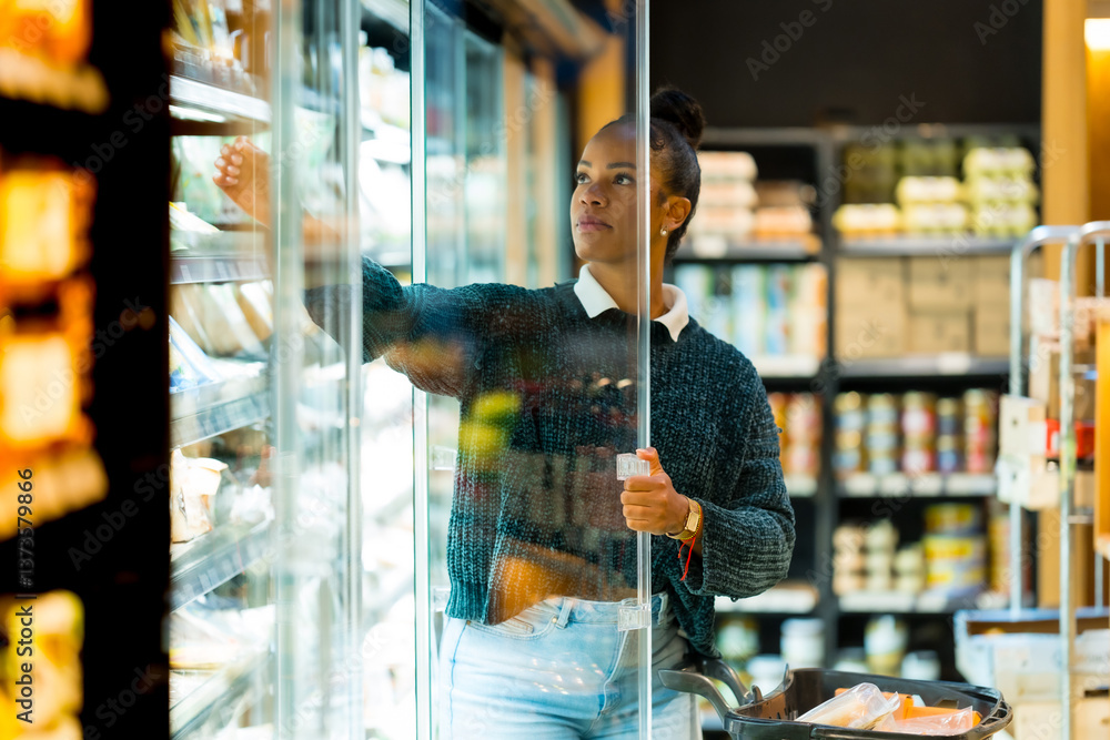 Woman choosing food from refrigerated display in supermarket