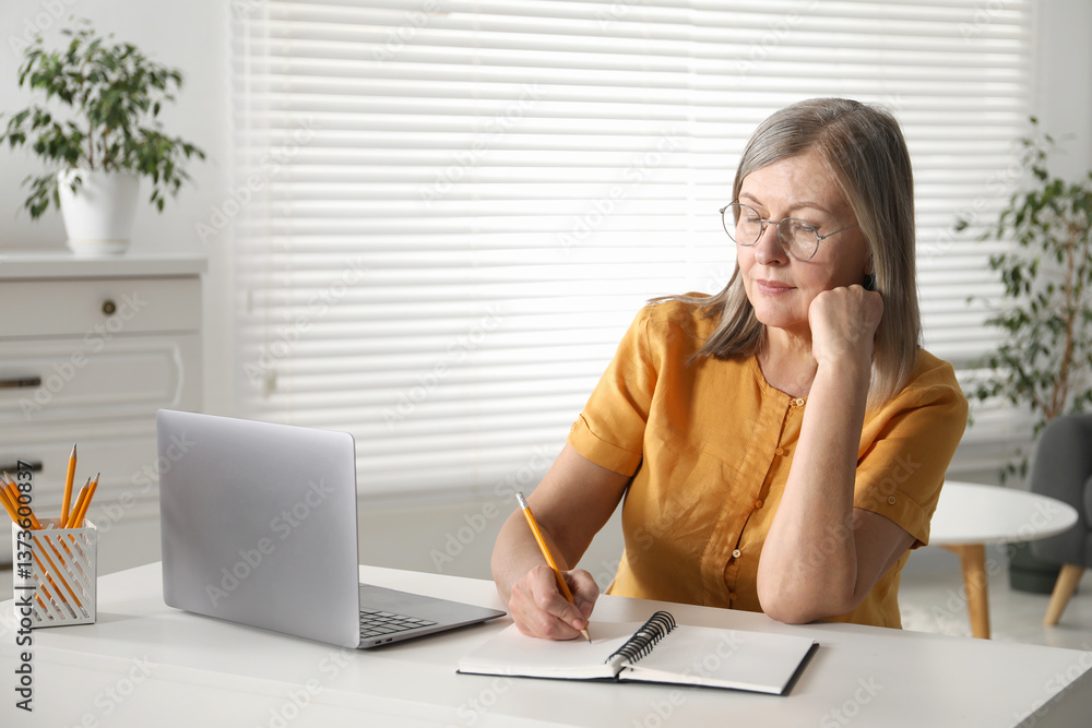 Woman learning online using laptop and taking notes at table indoors. Self-study Woman learning online using laptop and taking notes at table indoors. Self-study