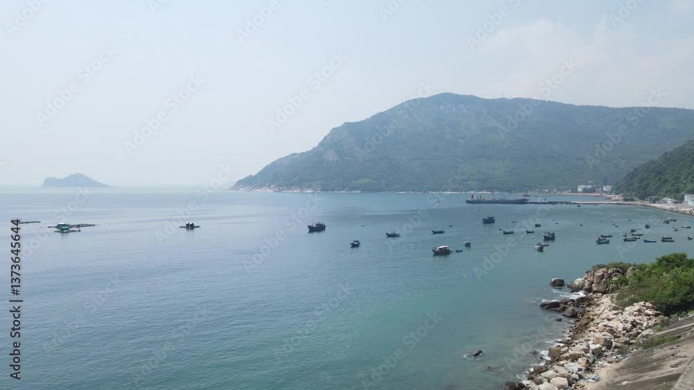 Calm sea with fishing boats floating near fish farms. Small islands and distant ships visible on horizon. Clear sky and blue water create peaceful atmosphere along coastal area in China. Calm sea with fishing boats floating near fish farms. Small islands and distant ships visible on horizon. Clear sky and blue water create peaceful atmosphere along coastal area in China.