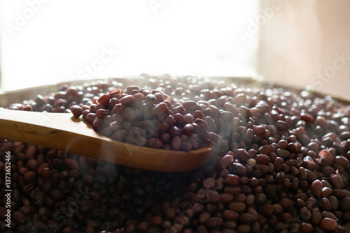 Hot cooked adzuki  beans (azuki beans or red kidney beans) on bamboo basket with smoke on a table close up morning light selective focus blur background, preparing for making tempe (tempeh)