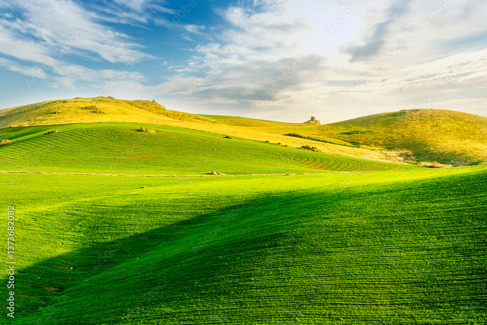 Naklejka premium scenery rural view of a contryside farm in green fields and hills with amazing cloudy sky on background