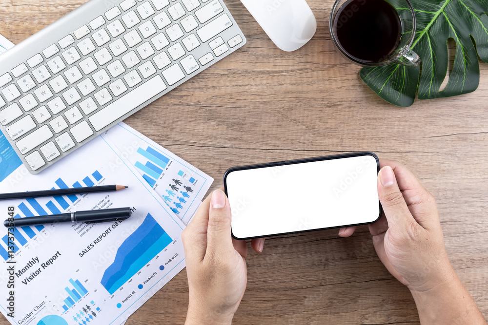 Obraz premium Top view of man's hand using smartphone with blank screen on wooden desk