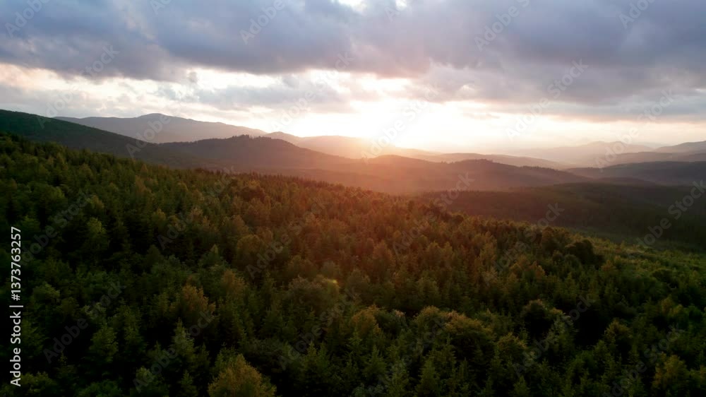 Aerial view breathtaking sunset over forest. Sun's rays break through dramatic clouds, casting golden glow across rolling hills and valleys. Distant mountains creating serene and picturesque scene. Aerial view breathtaking sunset over forest. Sun's rays break through dramatic clouds, casting golden glow across rolling hills and valleys. Distant mountains creating serene and picturesque scene.