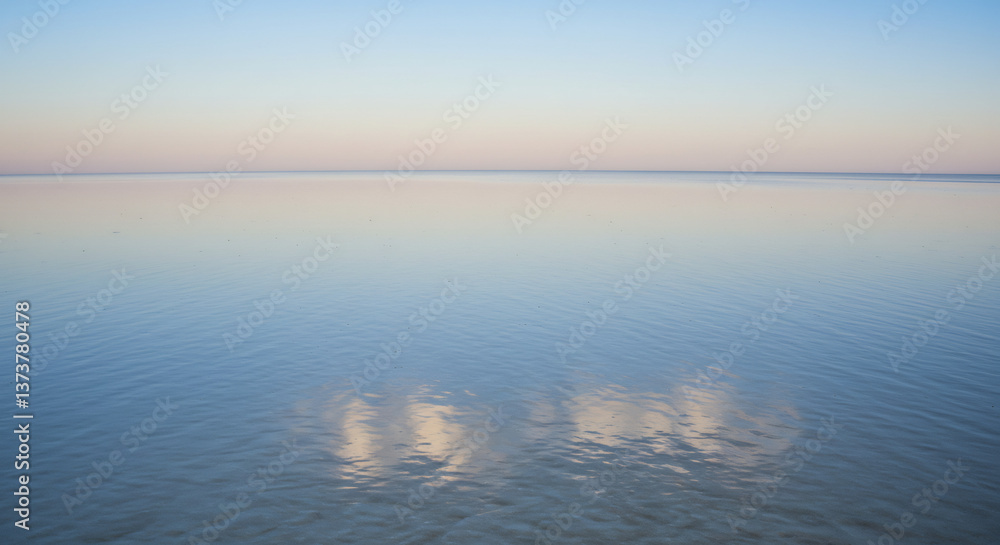 Obraz premium A smooth, still water surface under a soft gradient sky, creating a peaceful view.