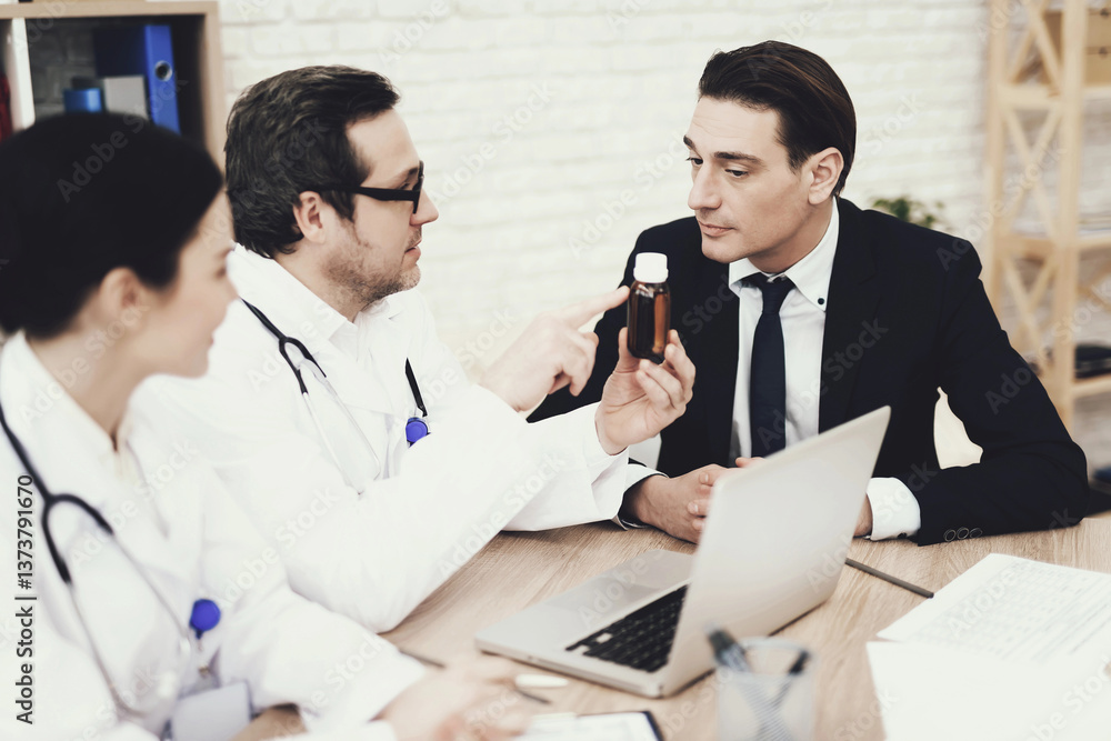 Experienced physician prescribes medicine for coughing to businessman in medical office. Experienced physician prescribes medicine for coughing to businessman in medical office.