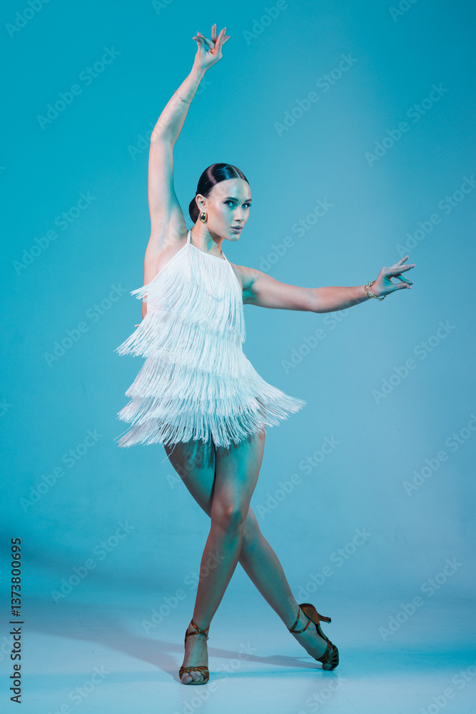 Naklejka premium Elegant dancer in fringed dress dancing solo salsa dance showing dramatic pose under artistic lighting