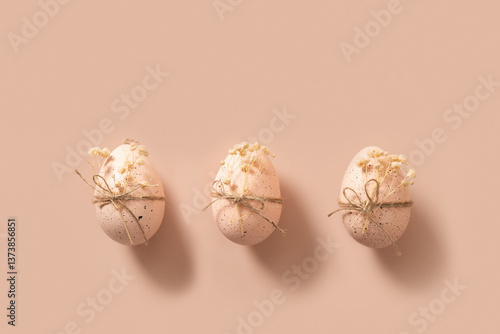 Obraz na płótnie Easter three chicken pink eggs decorated white gypsophila flowers with twine on beige pink nude background. View from above. Minimal concept. Copy space. w salonie