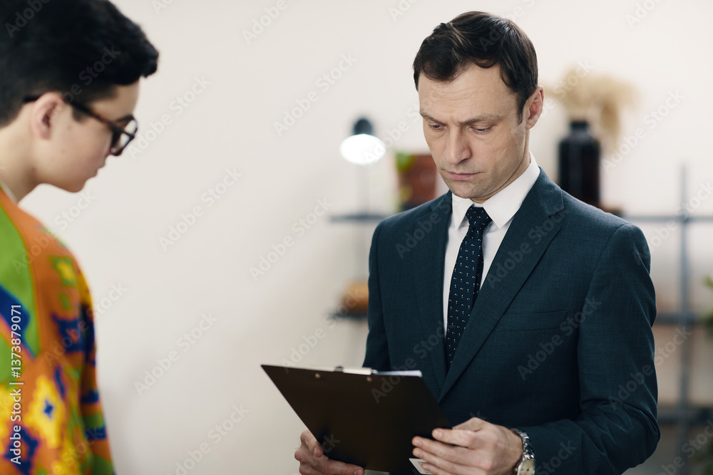 Manager reading resume of job candidate while they having meeting in office Manager reading resume of job candidate while they having meeting in office