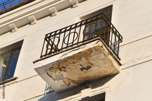 Obraz na płótnie Historic building with damaged balcony, rusted ironwork and peeling concrete, infrastructure deterioration. Decayed residential balcony with structural damage and corroded metal railing. Wear and tear w salonie