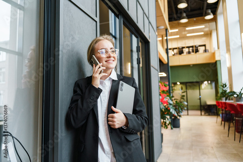 Business professional on phone in modern office setting with laptop during work hours
