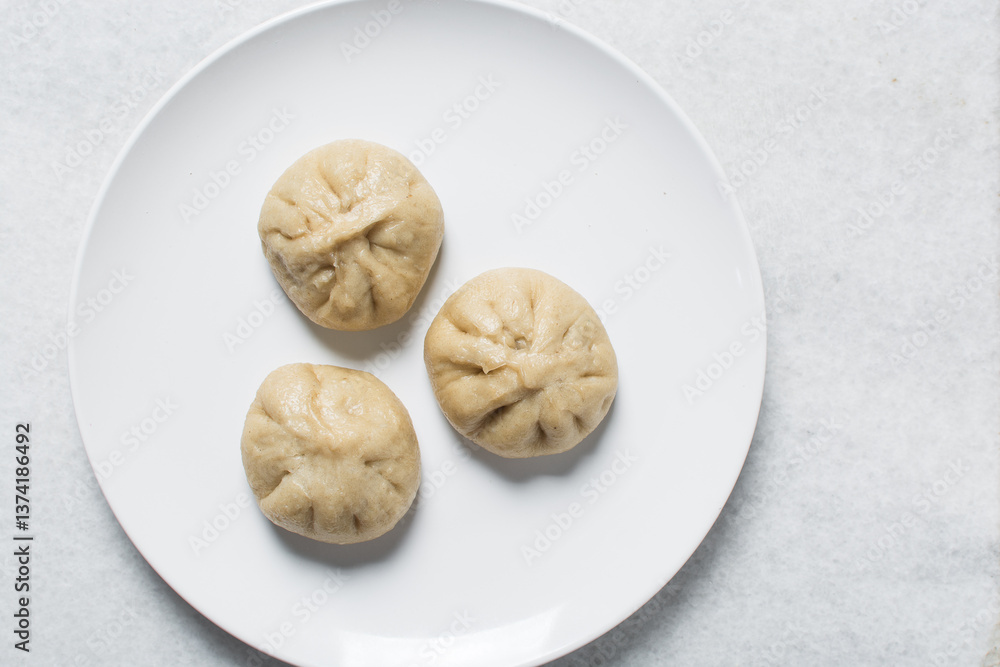 Overhead view of chicken bao on a white plate, top view of baozi, process of making homemade baozi Overhead view of chicken bao on a white plate, top view of baozi, process of making homemade baozi