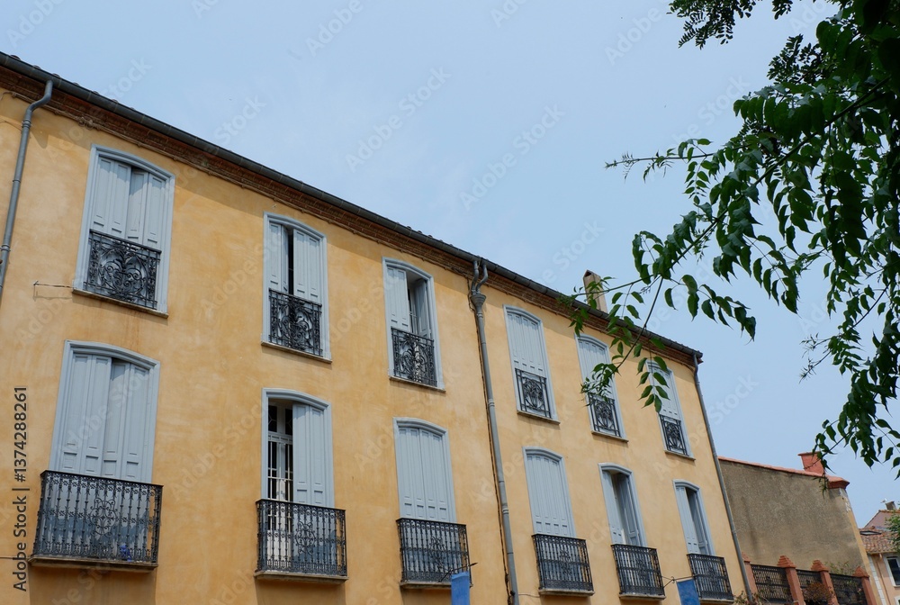 Fototapeta premium The charming yellow building features multiple balconies adorned with intricate ironwork