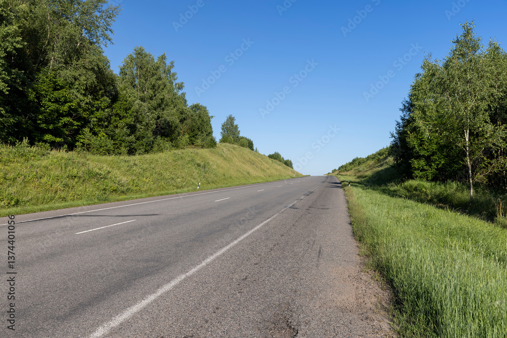 Fototapeta premium an empty straight paved road against a blue sky background