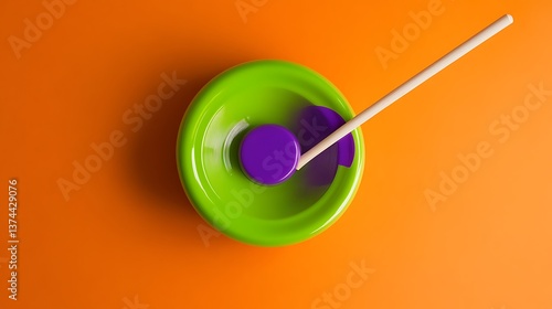 purple and green plastic diabolo with two wooden sticks and a white string ready to juggle on a orange background