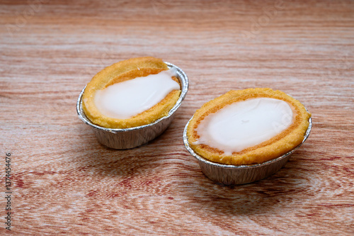 Two mazarin tarts sit on a wooden surface, showcasing their crispy golden edges and creamy white filling. Perfect for dessert lovers at a local market