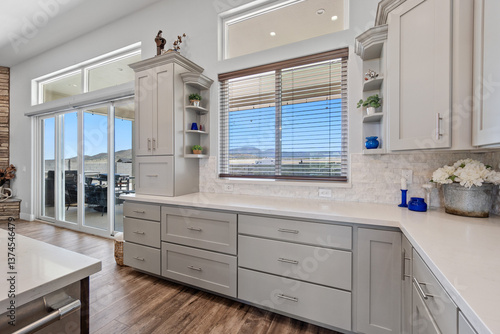 Fotografija A kitchen with white cabinets, countertops, and sliding glass doors