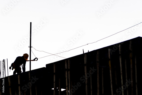 Construction site, silhouettes of construction industry workers on scaffolding against the sunset light. Constructing and building industry in Brazil
