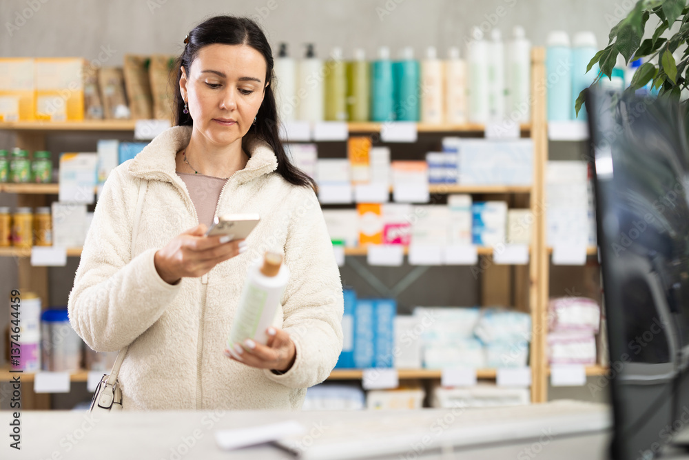 Woman scans the barcode of a cream package in a pharmacy and makes purchases using an app on her phone Woman scans the barcode of a cream package in a pharmacy and makes purchases using an app on her phone