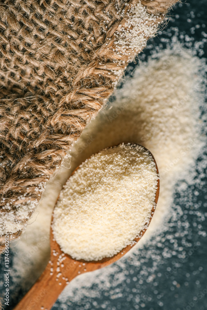 Close-up of semolina in a wooden spoon with a bowl in the background. Soft natural lighting enhances the fine texture and warm tones