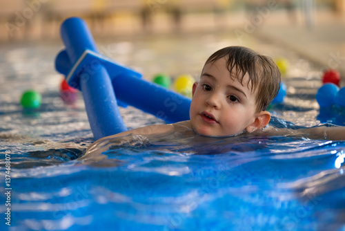 Child swimming with floatation device in indoor pool