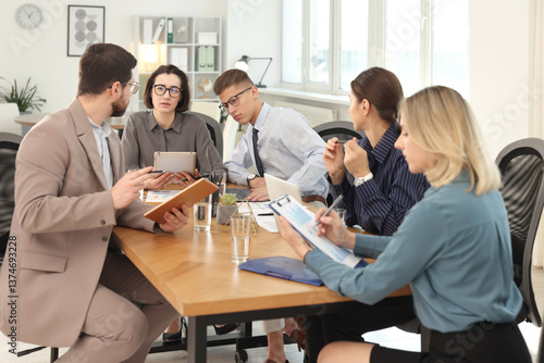 Coworkers working together at wooden table in office