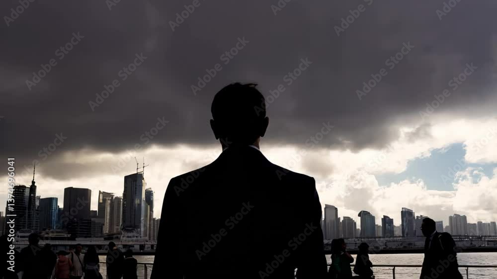 Silhouette of a man standing still under dramatic stormy skies in a bustling city waterfront
Silhouette of a man standing still under dramatic stormy skies in a bustling city waterfront