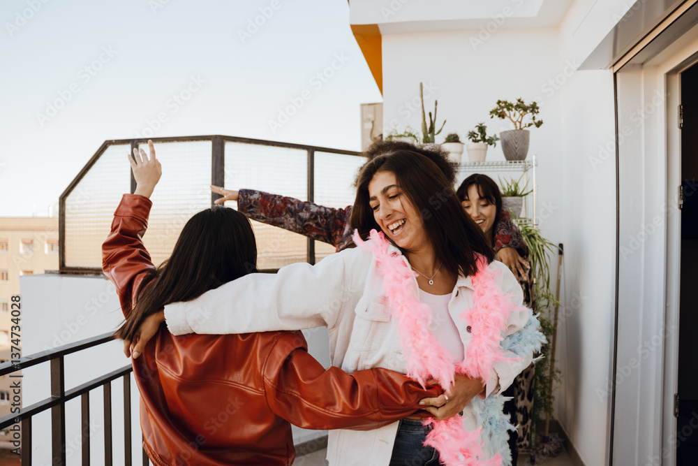 Fototapeta premium Group of four female friends dancing and laughing, on a balcony, at a girls' party