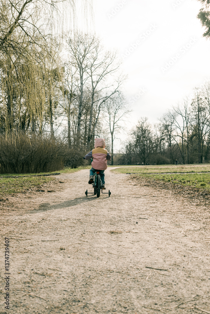 Little girl cycling on path in spring park Little girl cycling on path in spring park