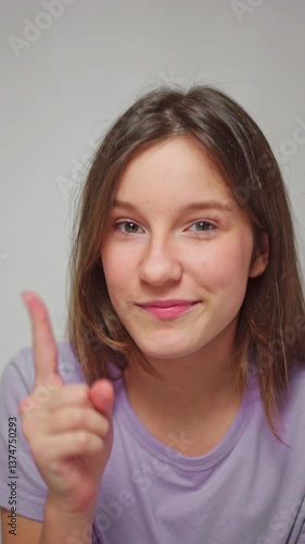 Wallpaper Mural Close-up studio shot of a girl playfully wagging her finger with a mischievous smile, as if teasing, on a white isolated background Torontodigital.ca