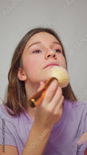 Wallpaper Mural Close-up studio shot of a girl applying powder with a brush as part of her makeup routine, on a white isolated background Torontodigital.ca