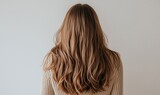 Back view of a woman with dry and frizzy hair before shampooing in studio shot.