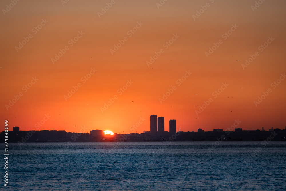 The sun sets over the buildings by the sea. sunset time. The sun sets over the buildings by the sea. sunset time.
