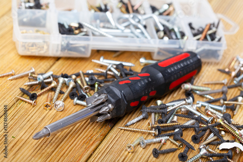Konstfotografi Screwdriver with magnetic tip and various metal self-tapping screws on wooden ta