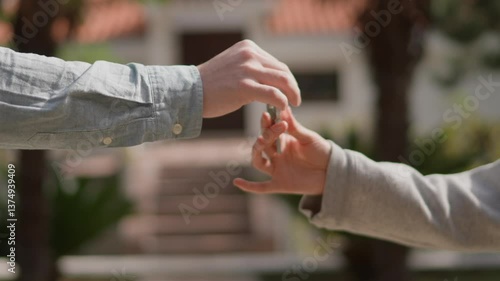 Close up Asian American female hand passing key male outdoors sunlight. Woman handing keys new house man customer. Buying dwelling. Selling home. Real-estate agent job. Handing over keys young couple.