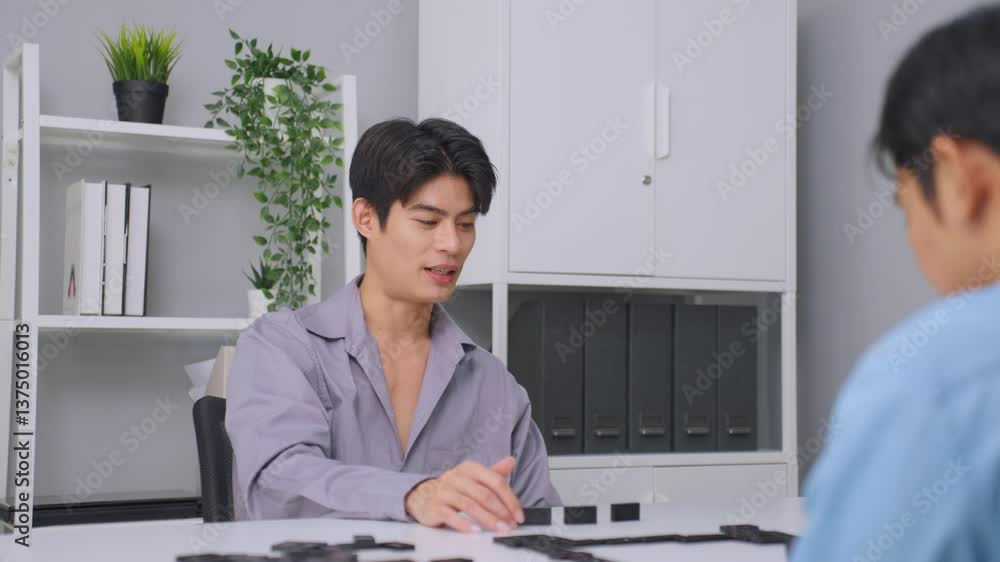 Asian young man playing board game during competition in community club. Asian young man playing board game during competition in community club.
