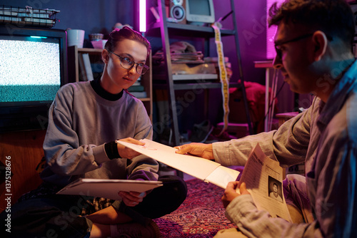 Young man and woman examining white folders labeled top secret while working together sitting on floor