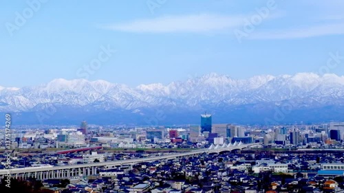 2021年2月上り北陸新幹線走る富山市街地の背景に広がる北アルプス立山連峰の山々