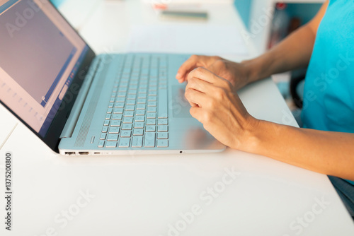 The hands of a woman, physiotherapist, on the keyboard of a laptop, on a table of his clinic's office