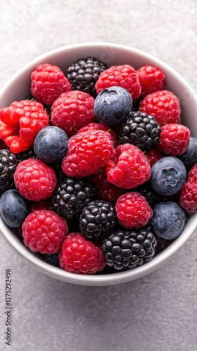 Bowl of fresh mixed berries on gray background