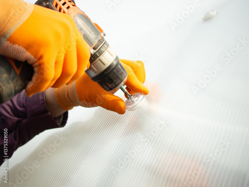A man assembles a new greenhouse from polyethylene and polycarbonate